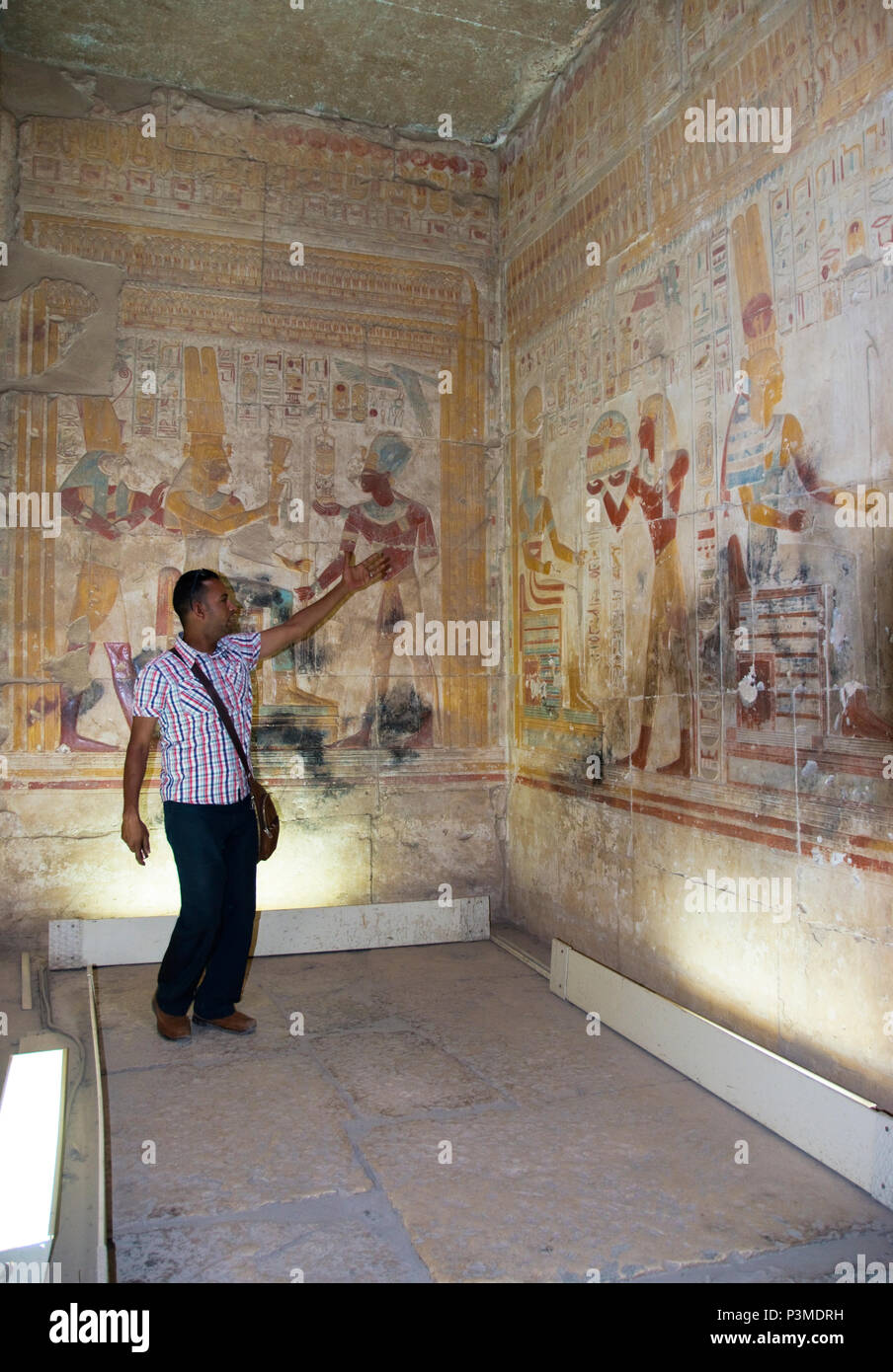 An Egyptian tour guide describes colorful bas relief stone carvings inside the Great Osiris Temple, Abydos, Egypt. Stock Photo