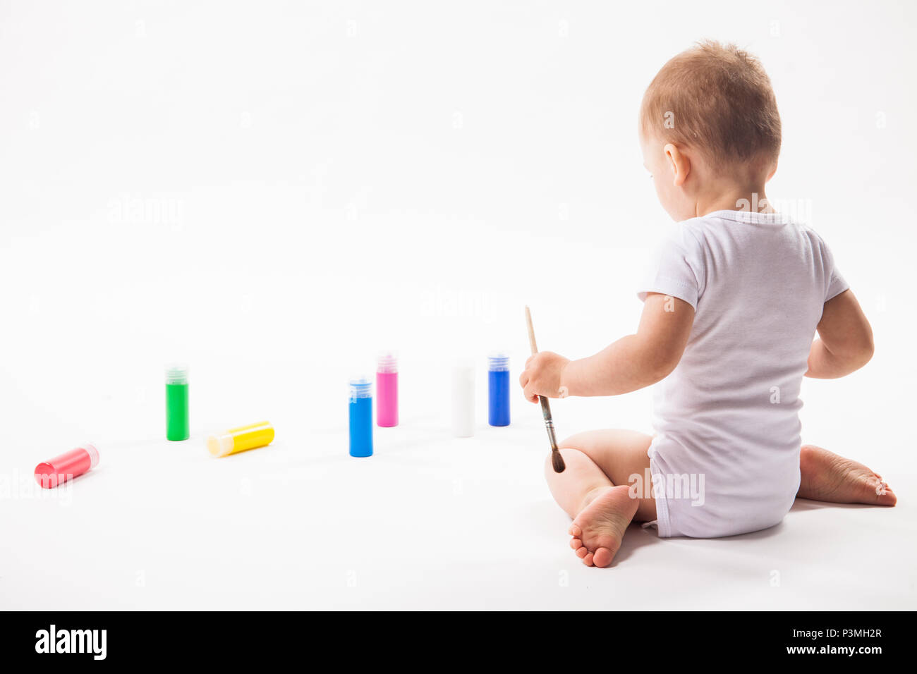 Cute little baby painting with paintbrush and colorful paints on white background Stock Photo
