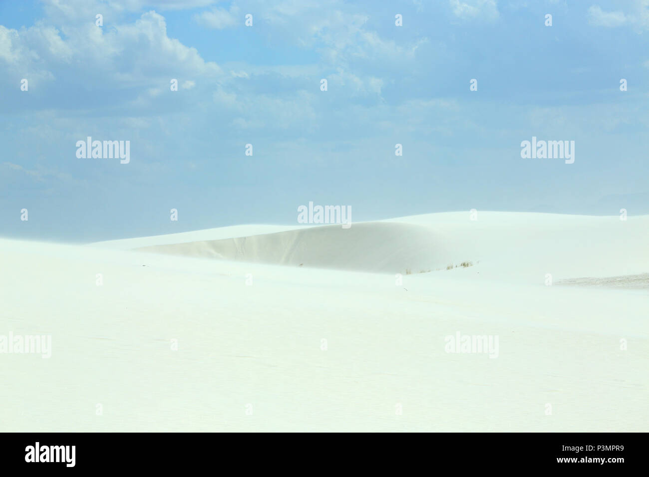 White sand dunes with wind formed ripples on a day with blue skies and clouds Stock Photo