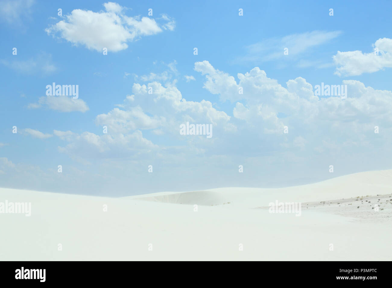 White sand dunes with wind formed ripples on a day with blue skies and clouds Stock Photo