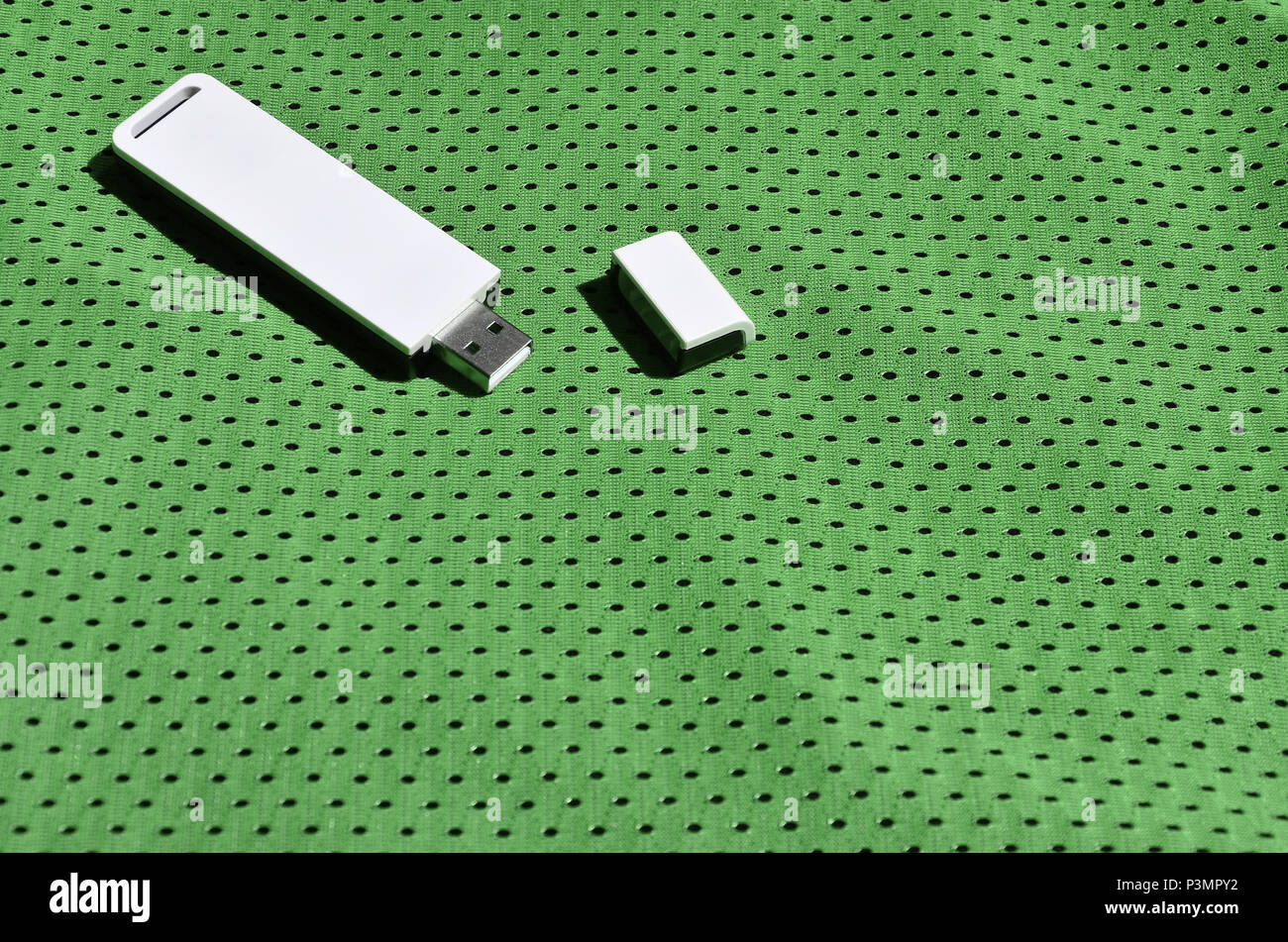 A modern portable USB wi-fi adapter is placed on the green sportswear made of polyester nylon fiber Stock Photo