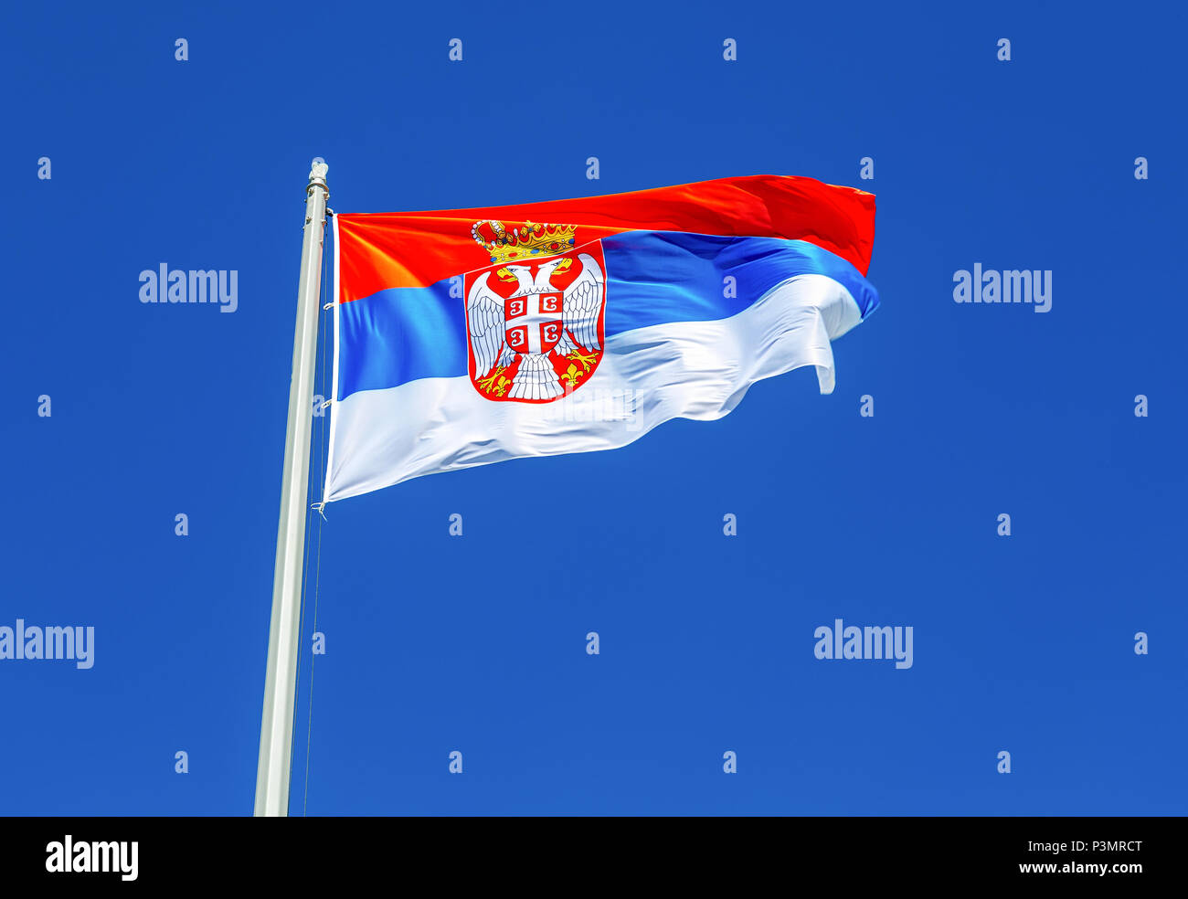 Flag of Serbia flying in the wind against the blue sky Stock Photo