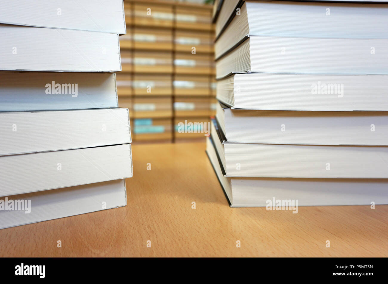Brand new white books stacked up on the wooden desk in the library.library cataloque in the background. Academic learn and knowledge concept Stock Photo