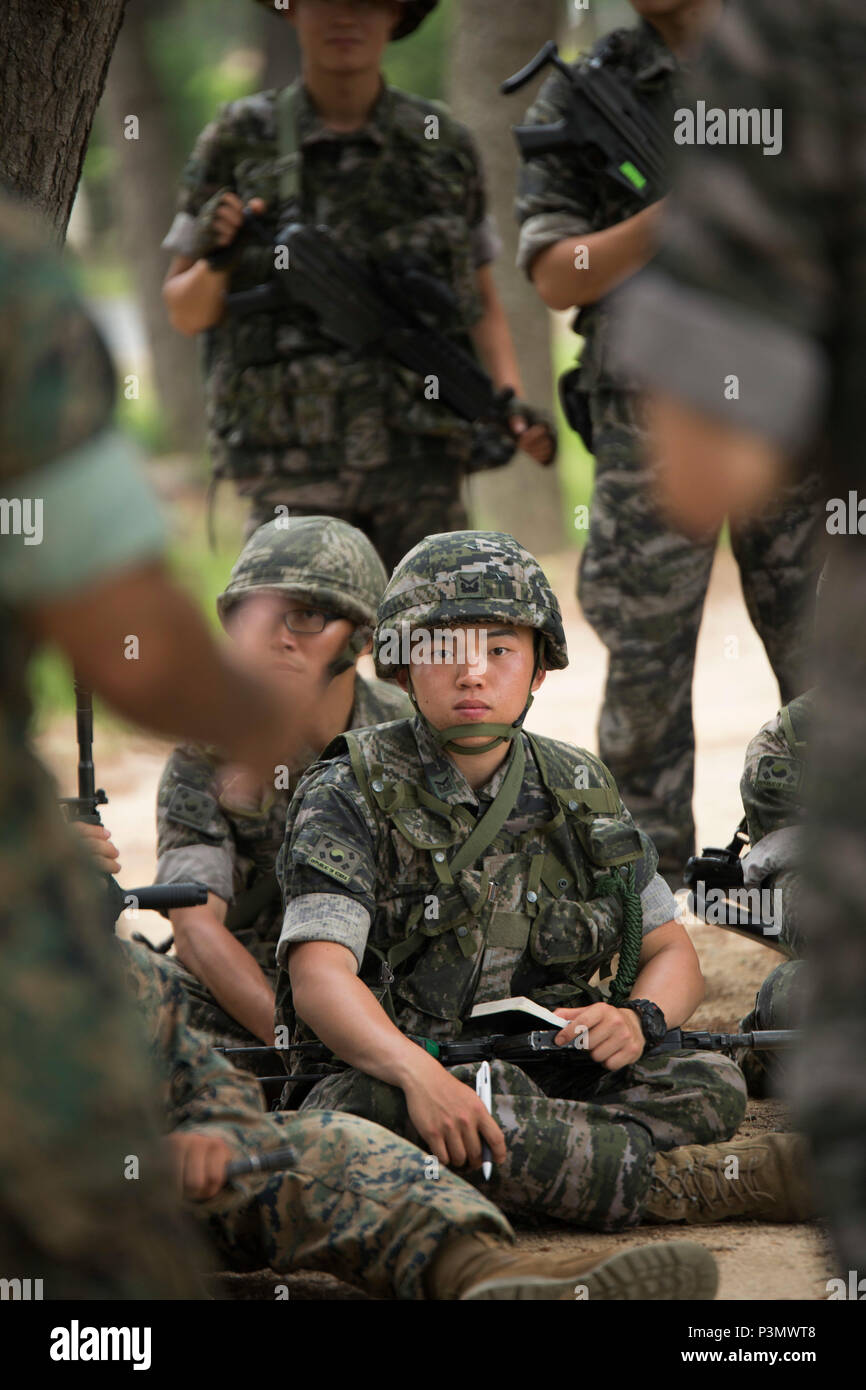 A Republic of Korea Marine sits and listens to a class on patrolling while keeping an eye out for improvised explosive devices amongst his peers and other U.S. Marines July 11, 2016 during Korean Marine Exchange Program 16-11. KMEP offers realistic training leveraging the most advanced tactics and technology to ensure a trained and ready ROK-U.S. combined force. The ROK Marines were a part of 73rd Battalion, 7th Regiment, 1st Marine Division. The U.S. Marines are with 2nd Battalion, 2nd Marine Regiment, currently assigned to 4th Marine Regiment, 3rd Marine Division, III Marine Expeditionary Fo Stock Photo