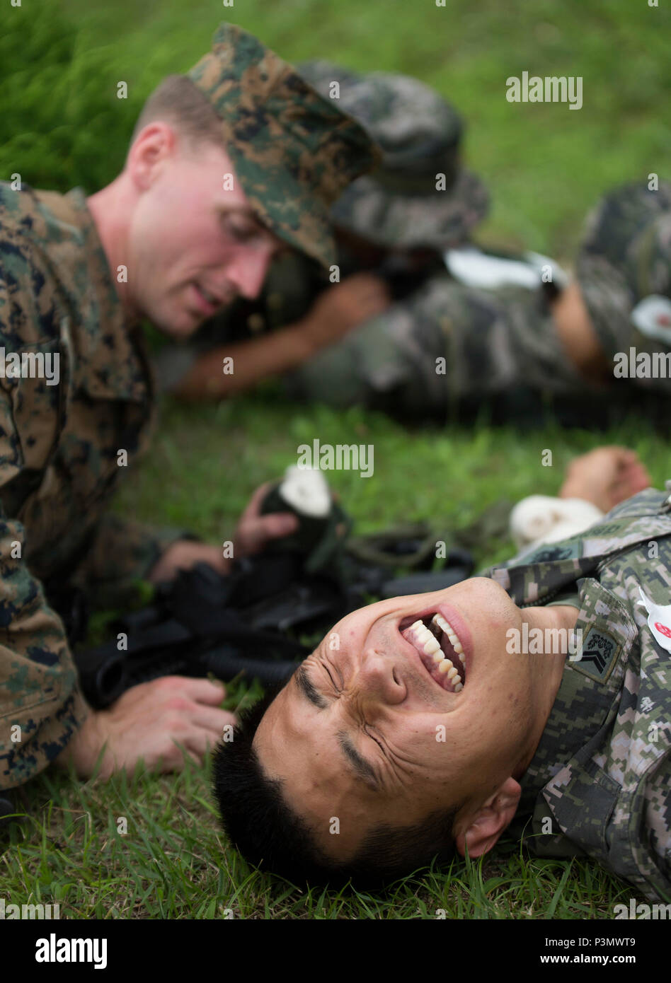 A Republic of Korea Marine yells in pretend pain as a U.S. Marine works to heal him during first aid during combat training July 11, 2016 during Korean Marine Exchange Program 16-11. KMEP offers realistic training leveraging the most advanced tactics and technology to ensure a trained and ready ROK-U.S. combined force. The ROK Marines were a part of 73rd Battalion, 7th Regiment, 1st Marine Division. The U.S. Marines participating in this training event are with 2nd Battalion, 2nd Marine Regiment, currently assigned to 4th Marine Regiment, 3rd Marine Division, III Marine Expeditionary Force thr Stock Photo