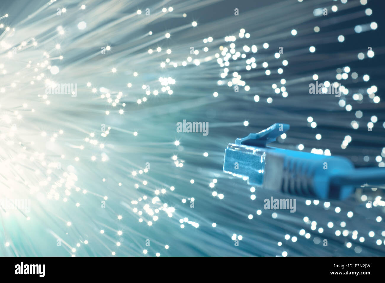 Futuristic technological background, closeup on the end of optical fiber network cable on turquoise background. Shallow DOF, partial focus on the plug Stock Photo