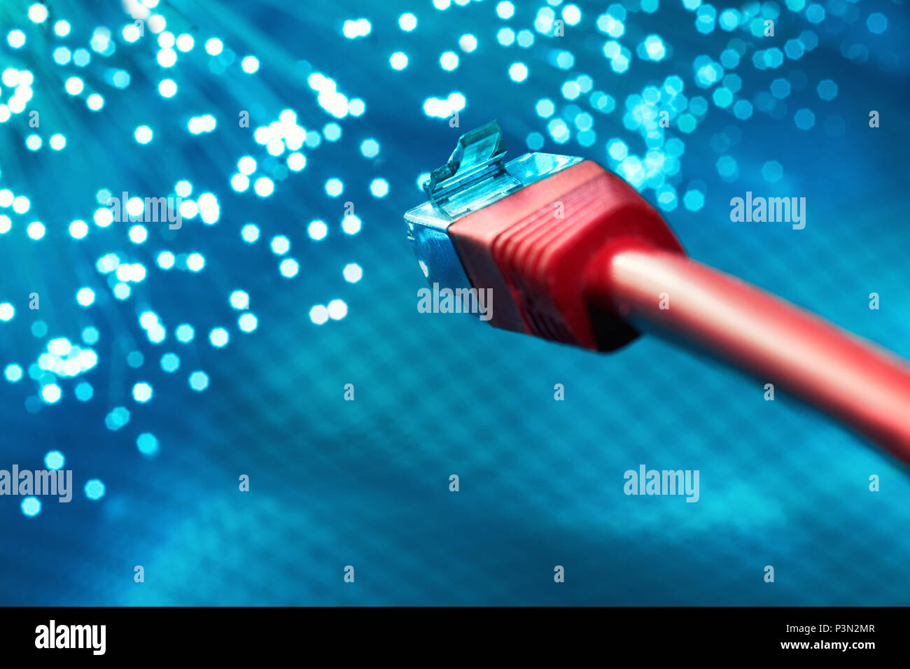 Futuristic technological background, closeup on the end of red optical fiber network cable on blue background Stock Photo