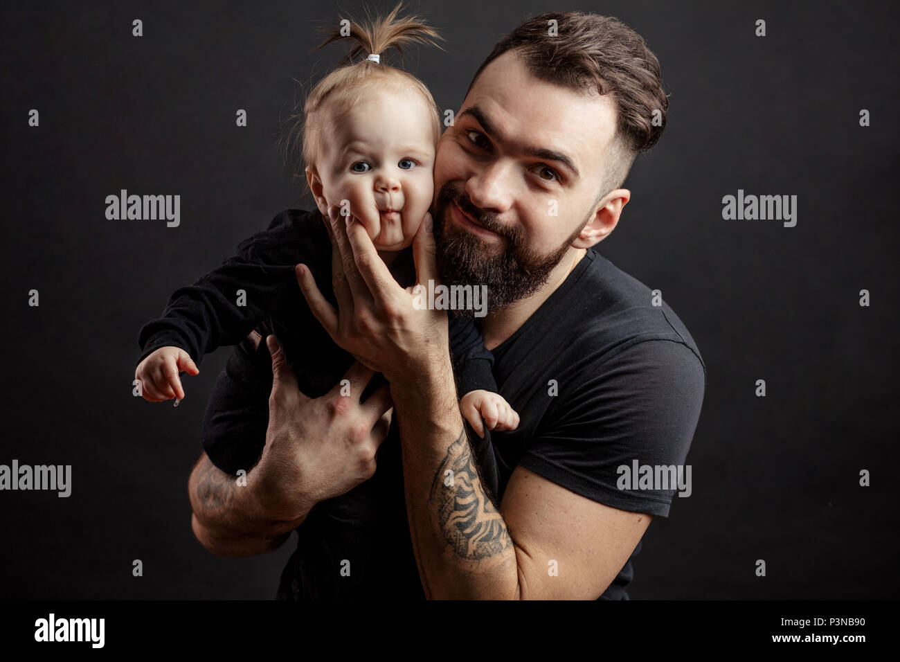 Young athletic father with adorable baby on black background Stock Photo