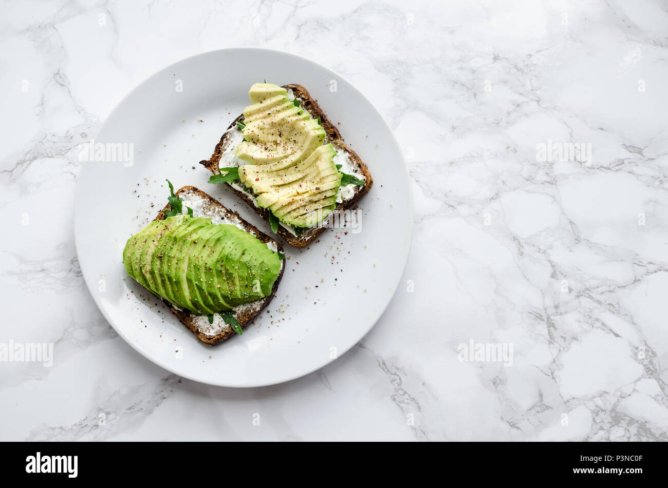 Avocado toasts on rye bread with sliced avocado, arugula, creme cheese