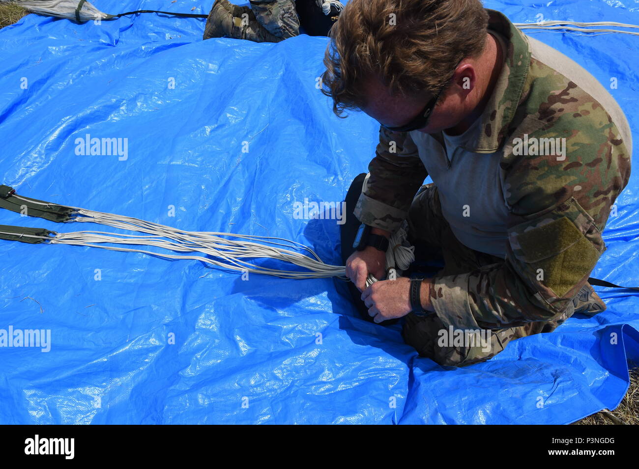 A combat controller with the 320th Special Tactics Squadron packs his parachute after a multi-aircraft, joint airborne operation with special operations assets and conventional forces from all four branches of the U.S. Armed Forces as part of Rim of the Pacific 2016 to strengthen their relationships and interoperability with their partners, Pohakuloa Training Area, Hawaii, July 14, 2016. Twenty-six nations, more than 40 ships and submarines, more than 200 aircraft and 25,000 personnel are participating in RIMPAC from June 30 to Aug. 4, in and around the Hawaiian Islands and Southern California Stock Photo