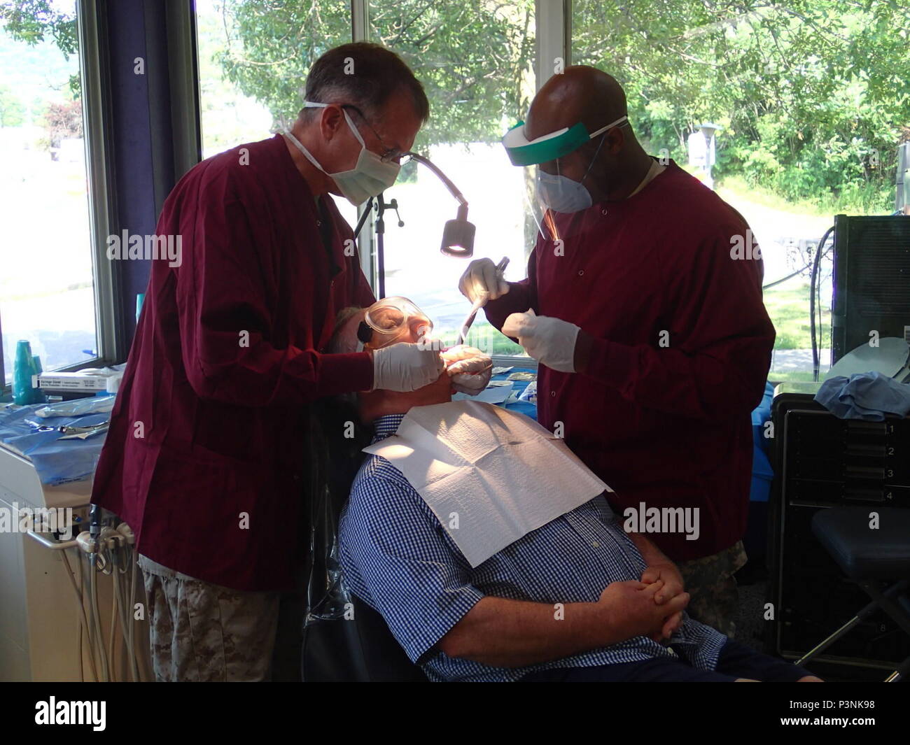 Lt. Blair Willcox, a Navy dentist from the 4th Dental Battalion, Fort Worth, Texas and Sgt. Jerome Capers, a dental technician from Company A, 48th Combat Support Hospital, Fort Story, Va., provide dental care during Greater Chenango Cares on July 15, 2016.  Greater Chenango Cares is one of the Innovative Readiness Training events which provides real-world training in a joint civil-military environment while delivering world class medical care to the people of Chenango County, N.Y., from July 15-24. Stock Photo
