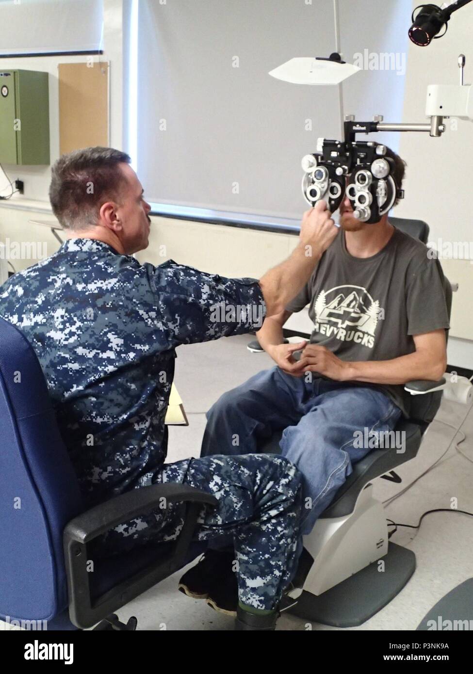 Capt. Philbrook Mason, an optometrist from the Navy Operational Support Center, Quincy, Mass., conducts an eye exam on a patient during Greater Chenango Cares on July 15, 2016.  Greater Chenango Cares is one of the Innovative Readiness Training missions which provides real-world training in a joint civil-military environment while delivering world class medical care to the people of Chenango County, N.Y., from July 15-24. Stock Photo