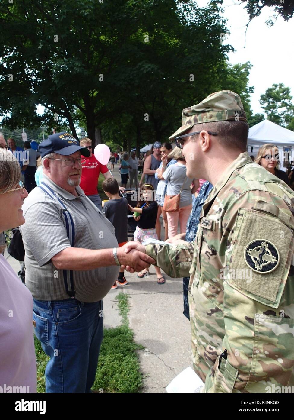 Army Capt. Lucas Marcum, a triage nurse from Company Bravo 48th Combat Support Hospital, Fort Meade, Md., speaks with community members at the Holiday in Homer festival about the Healthy Cortland event July 16, 2016.  Healthy Cortland is one of the Innovative Readiness Training events which provides real-world training in a joint civil-military environment while delivering world-class medical care to the people of Cortland, N.Y., from July 15-24. Stock Photo