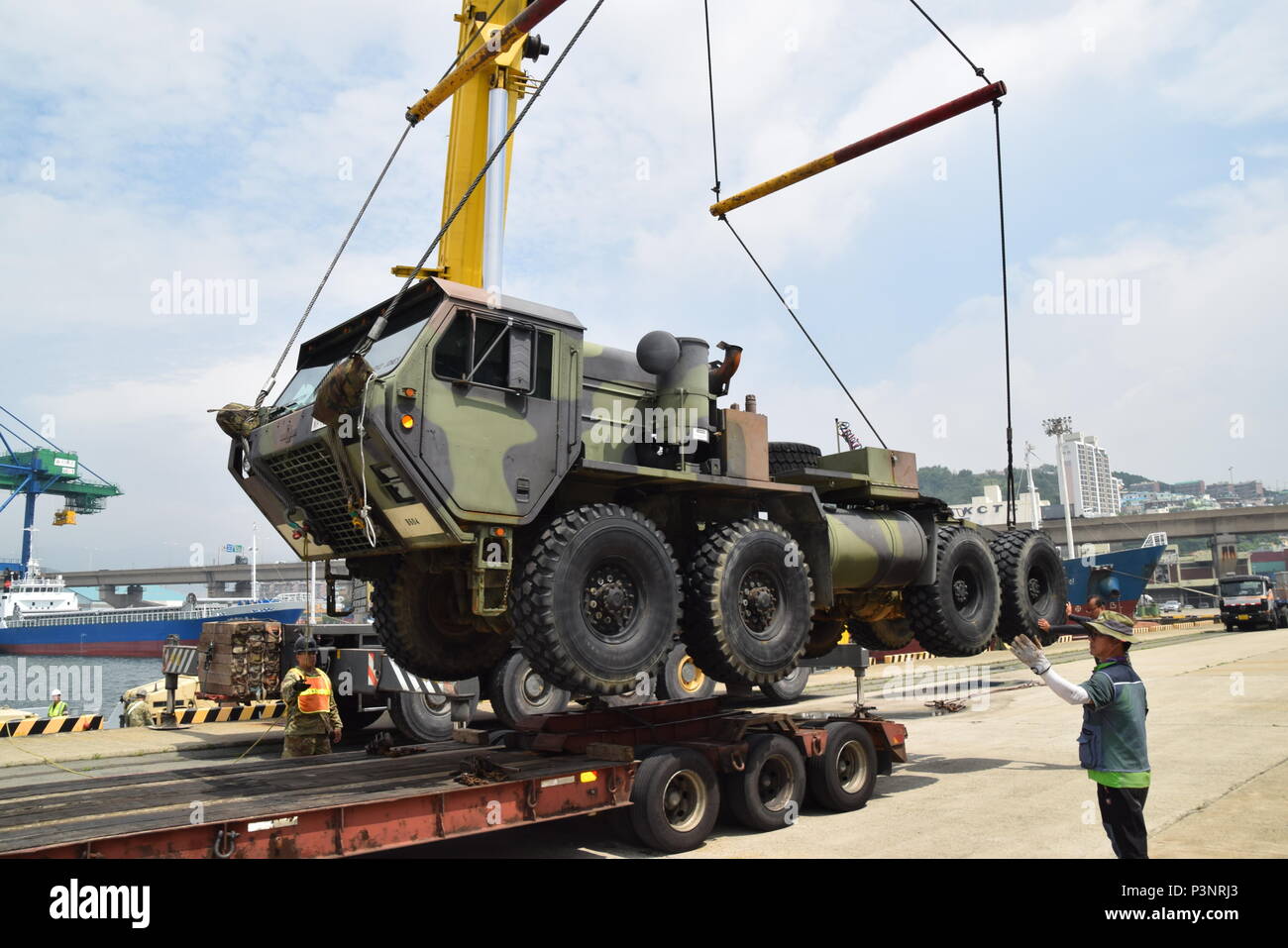 A Heavy Expanded Mobility Tactical Truck is crane lifted onto a flatbed