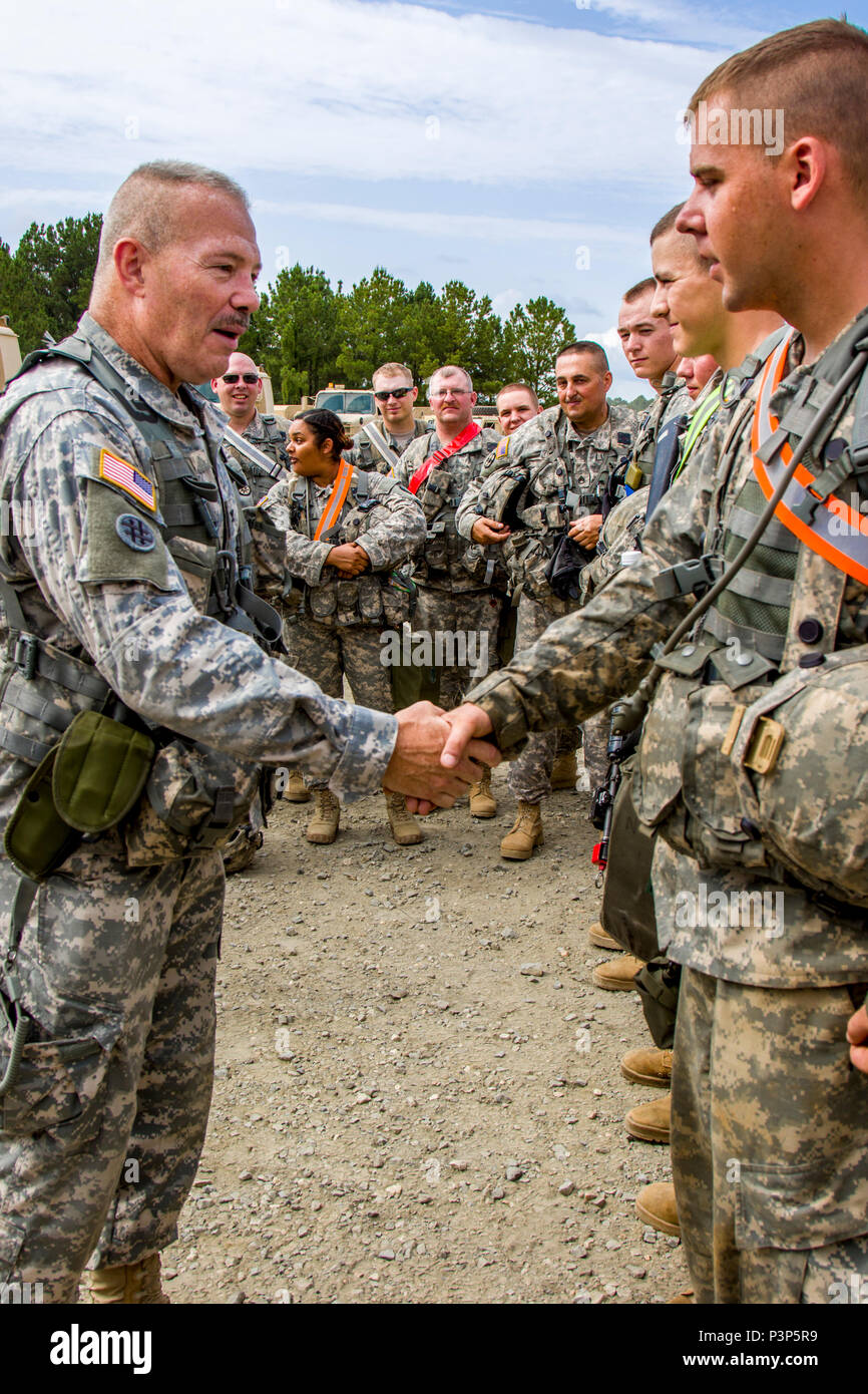 U.S. Army Reserve Col. Robert Benjamin, the commander of 655th Regional Support Command, presents a coin in recognition of outstanding ability to fix vehicle issues within 24 hours to  Spc. Tyler Harkins, all wheeled vehicle mechanic assigned to 220th Transportation Co., Keene, N.H., at the Army's Joint Readiness Training Center, Fort Polk, La., Saturday, July 16. The 220th Transportation Co. joined more than 5,000 Soldiers from other state Army National Guard units, active Army and Army Reserve troops as part of the 27th Infantry Brigade Combat Team task force, July 9-30, 2016. U.S. Army Nati Stock Photo