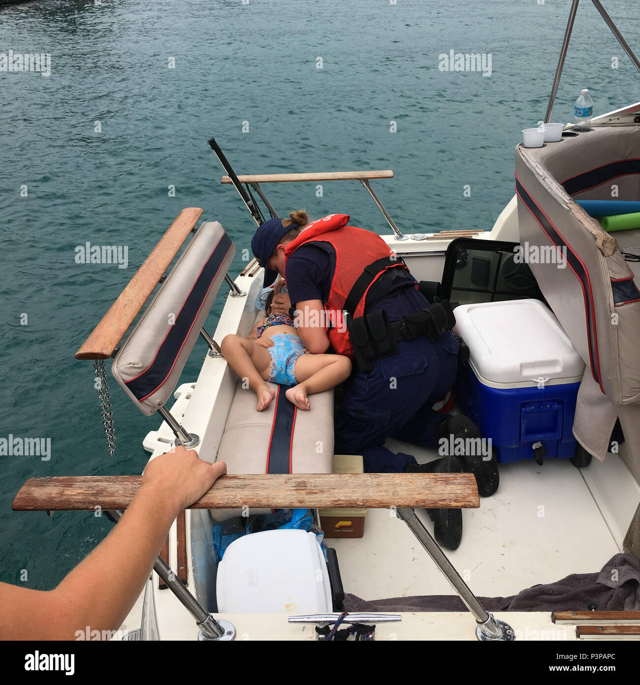 Seaman Amanda Wolf, a boat crew member from Coast Guard Station Wilmette Harbor in Chicago, Illinois, performs CPR on a child aboard a vessel in Lake Michigan, July 21, 2016. Wolf successfully resuscitated the girl while in transit to Navy Pier. (U.S. Coast Guard photo) Stock Photo