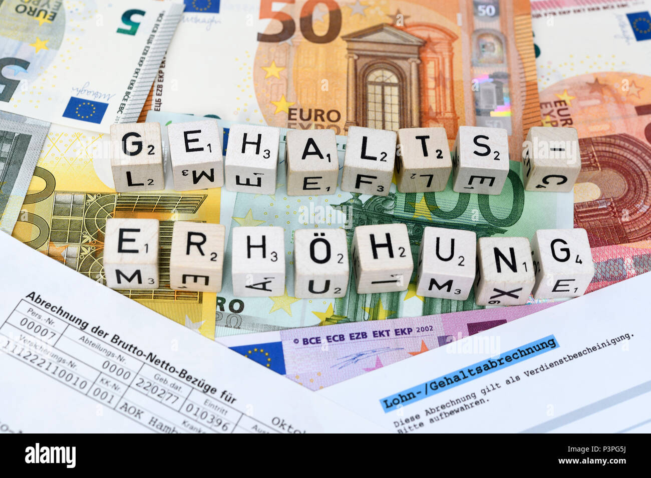 Letter cube forms the word salary increase on money, Buchstabenwürfel formen das Wort Gehaltserhöhung auf Geldscheinen Stock Photo