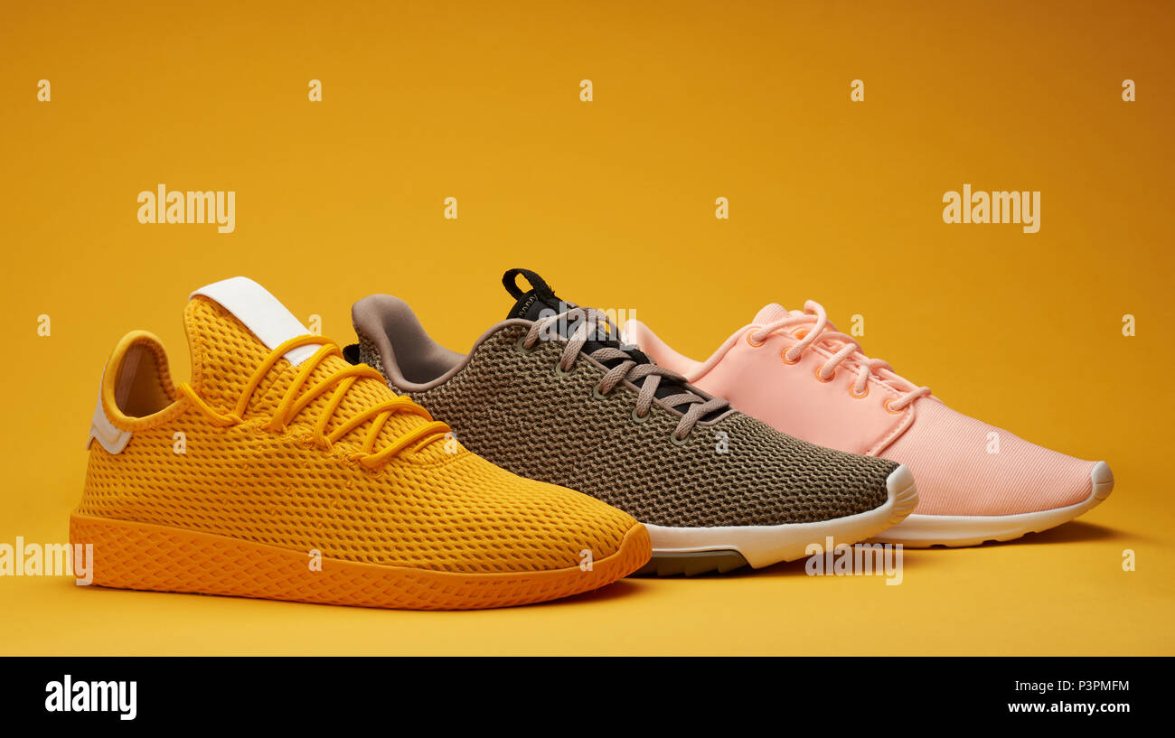 Different color running shoes on yellow background Stock Photo