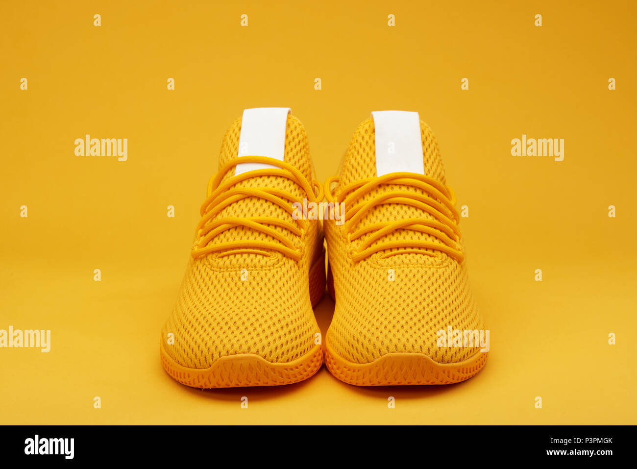 Front view of sport yellow  pair shoes on orange background Stock Photo