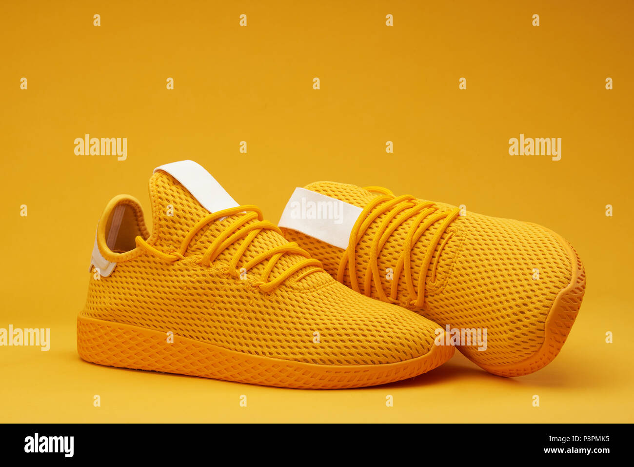 Yellow tennis modern shoes isolated on orange background Stock Photo