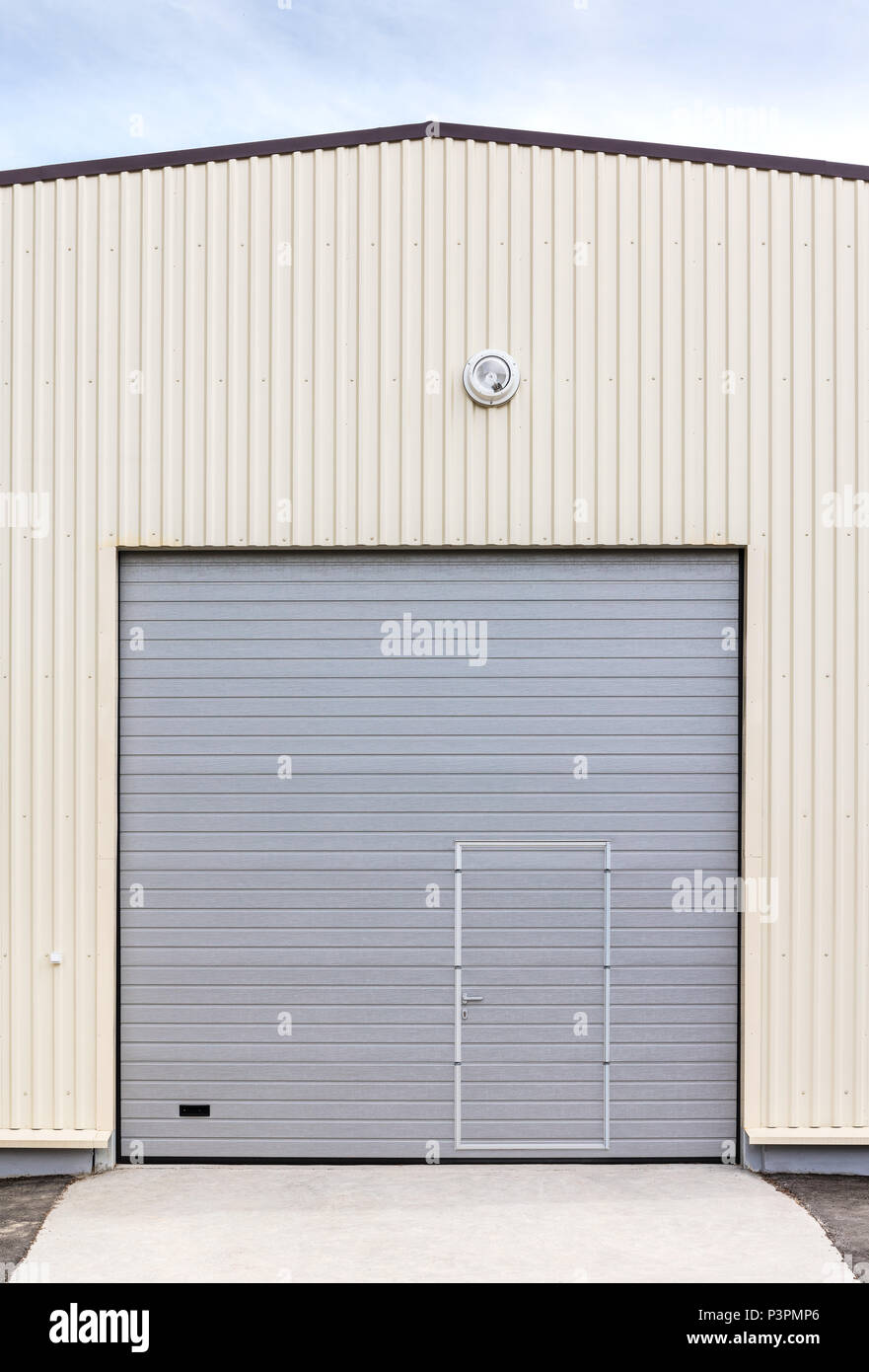 industrial warehouse exterior. closed gray metal gate with door Stock Photo