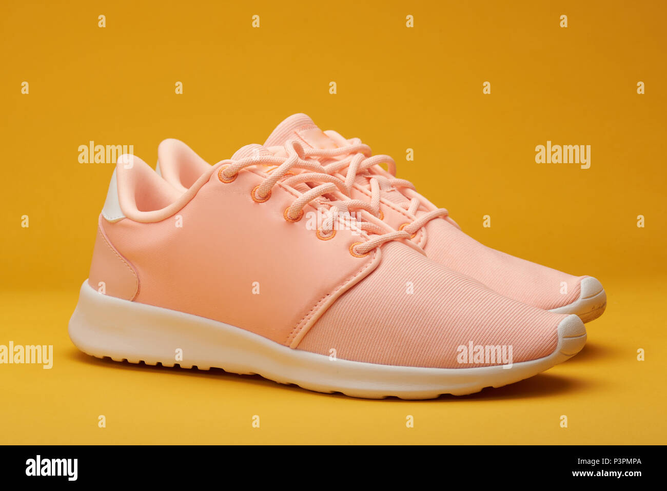 Close-up of pair pink sport shoes on yellow background Stock Photo