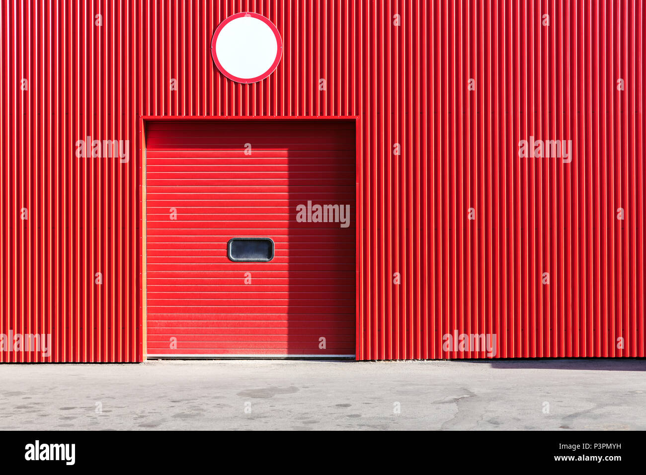 red metal warehouse wall with closed roller shutter door Stock Photo