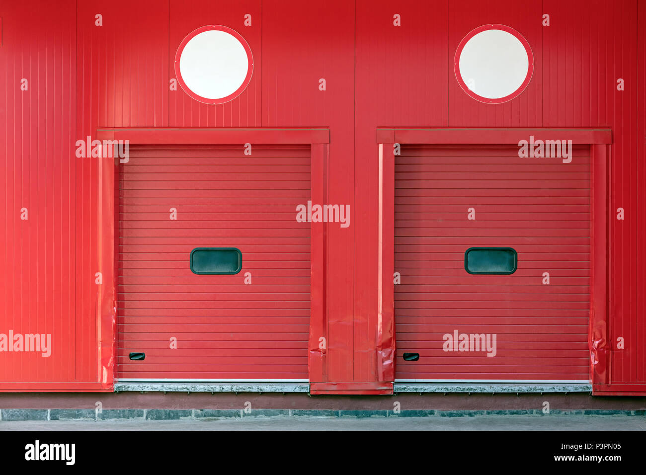 loading docks with closed shutter doors on red wall of distribution warehouse Stock Photo