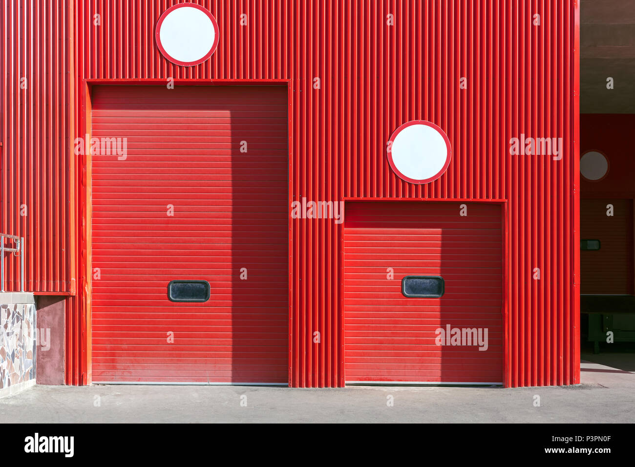 roller shutter gate of different size on red wall of distribution warehouse Stock Photo