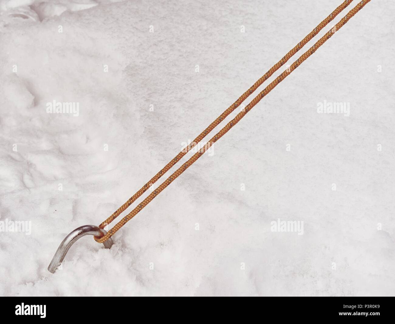 Chrome steel hook anchor camping tent in snow. Process of installing tent setting up tent outdoors. Stock Photo