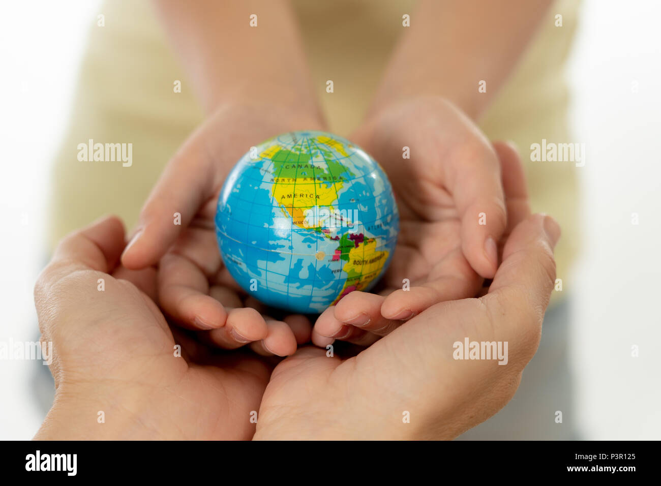 close up photo of mother and child holding hands with a world globe in their hands in better world idea protection and education concept Stock Photo