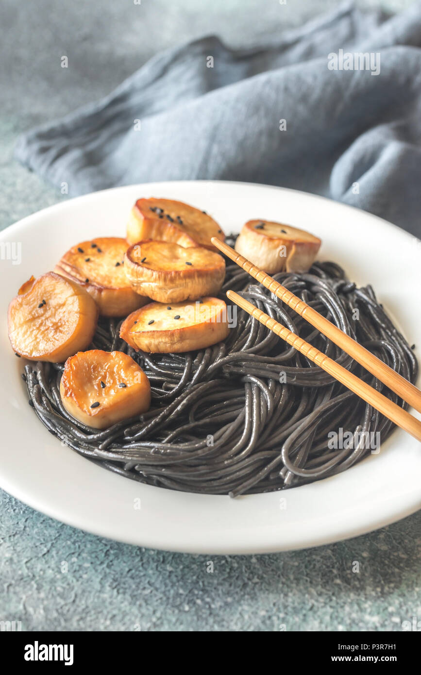 Portion of black pasta with king oyster scallops Stock Photo