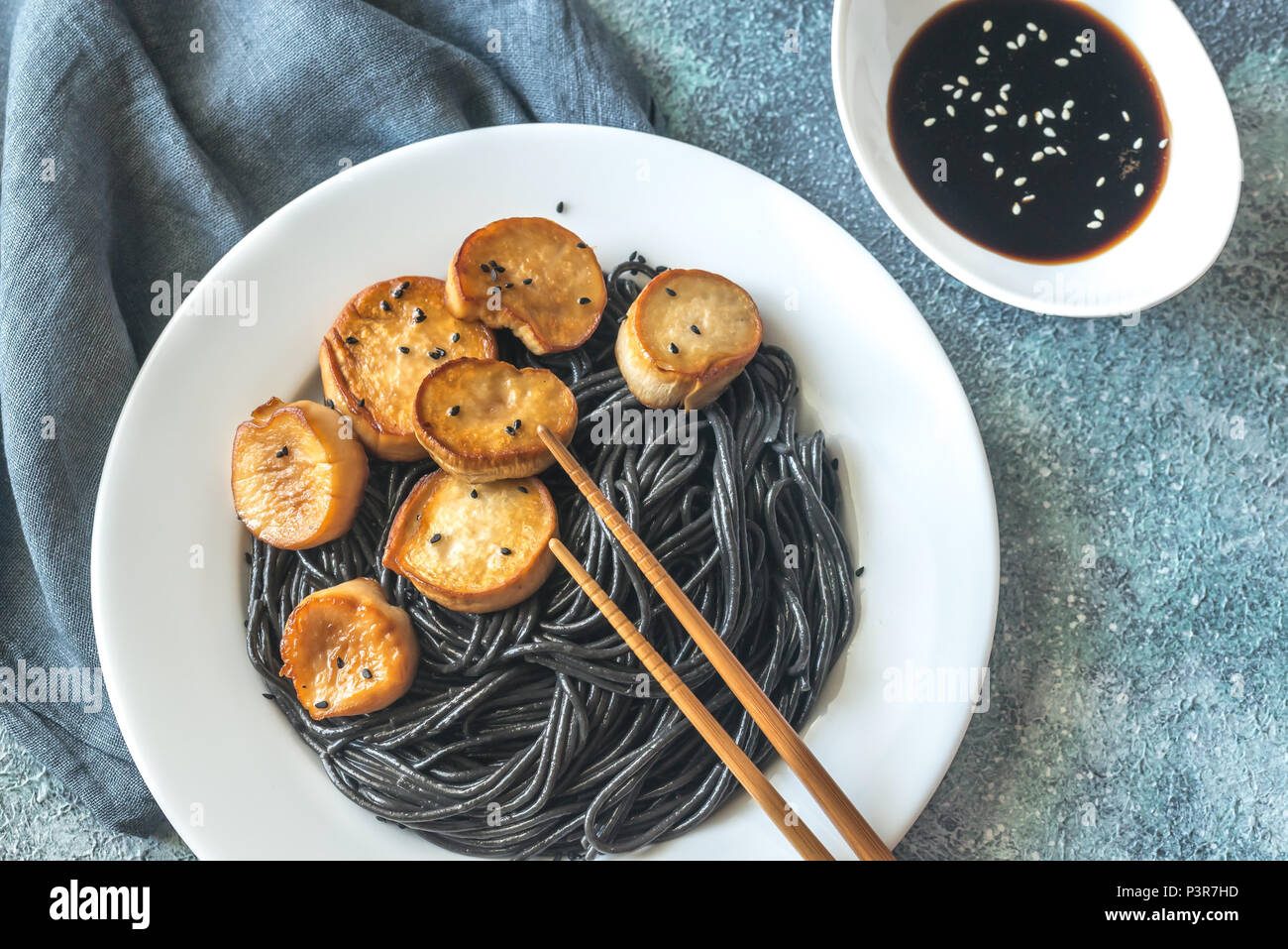 Portion of black pasta with king oyster scallops Stock Photo