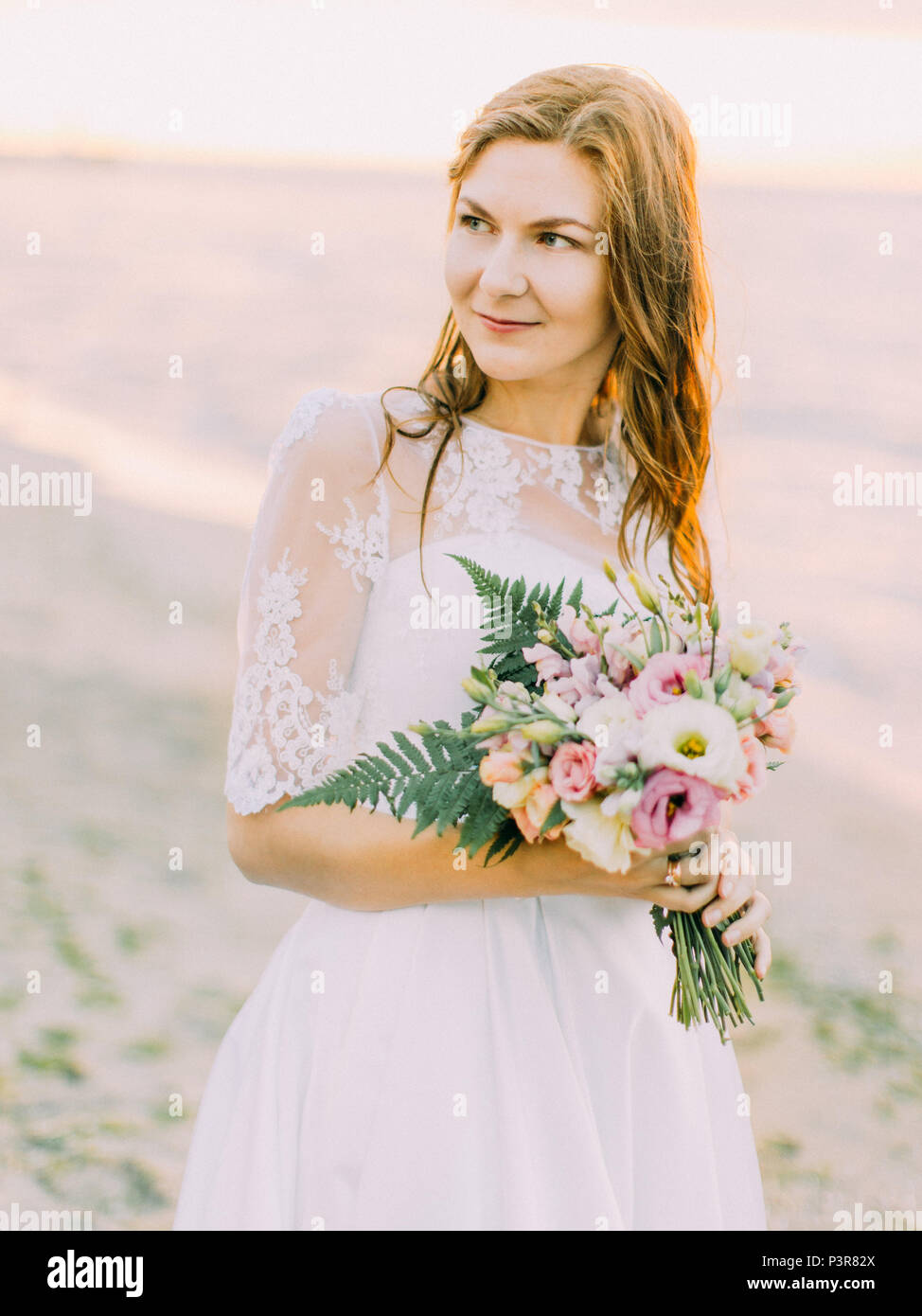 The portrait of the bride with the bouquet looking at the right side. The sunset composition. Stock Photo