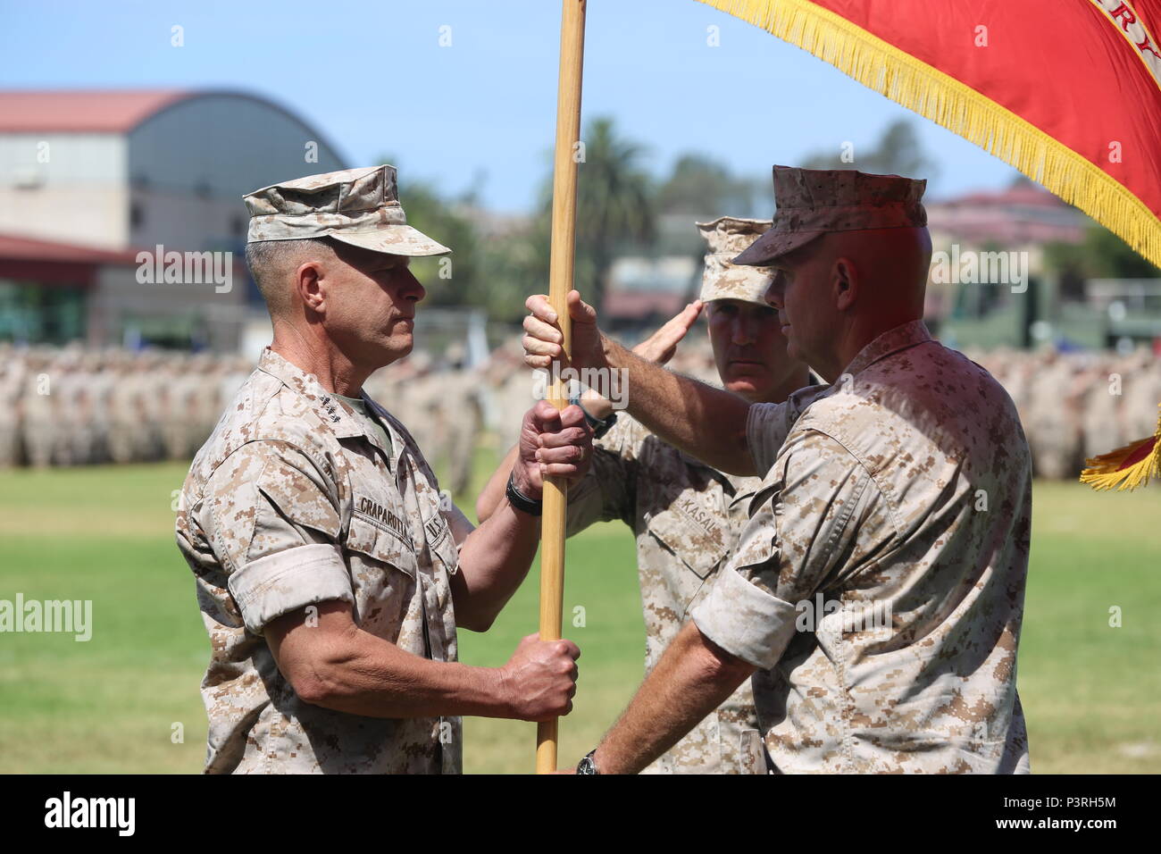 Lt. Gen. David H. Berger, the outgoing commanding general of I Marine  Expeditionary Force, passes the unit colors to Lt. Gen. Lewis A. Craparotta  during a change of command ceremony at Camp