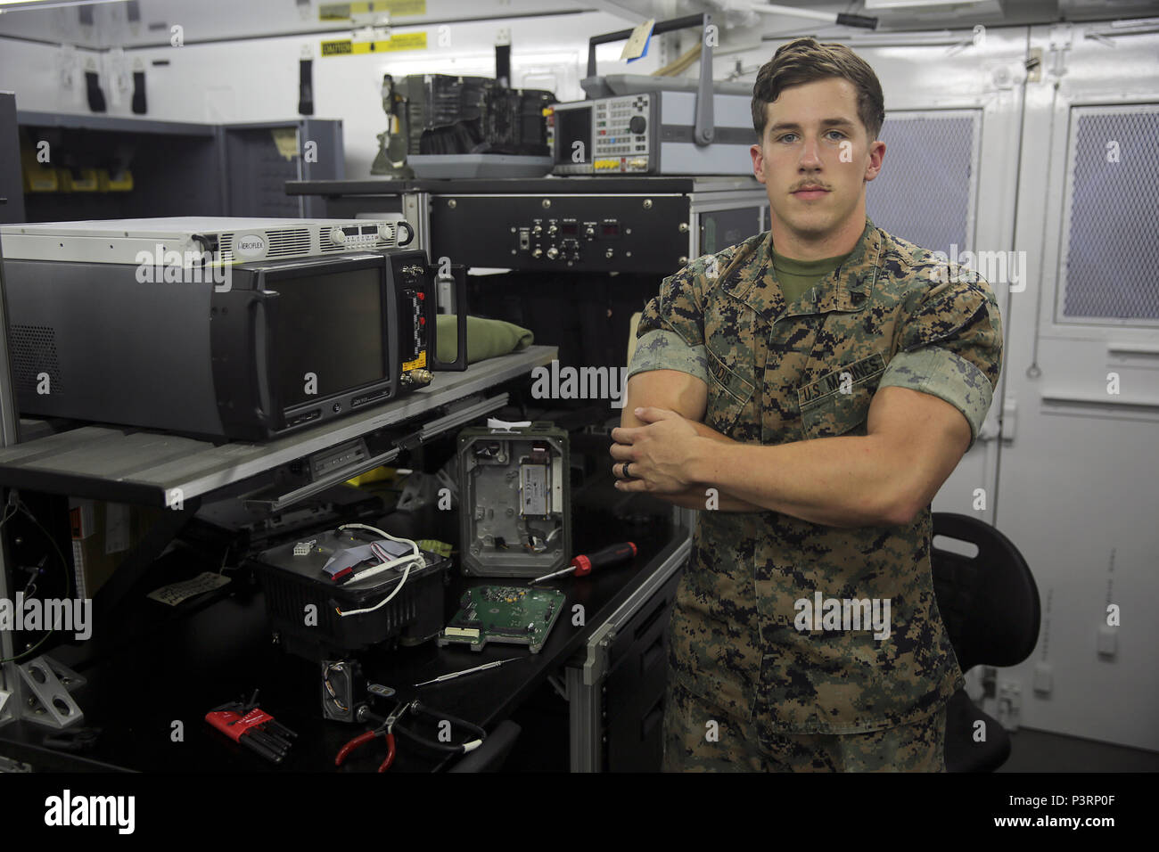 Cpl. Brandon Gaddis, a ground radio repair technician with Special Purpose  Marine Air-Ground Task Force Crisis Response-Africa, stands in front of his  work area at Naval Air Station Sigonella, Italy, July 27,