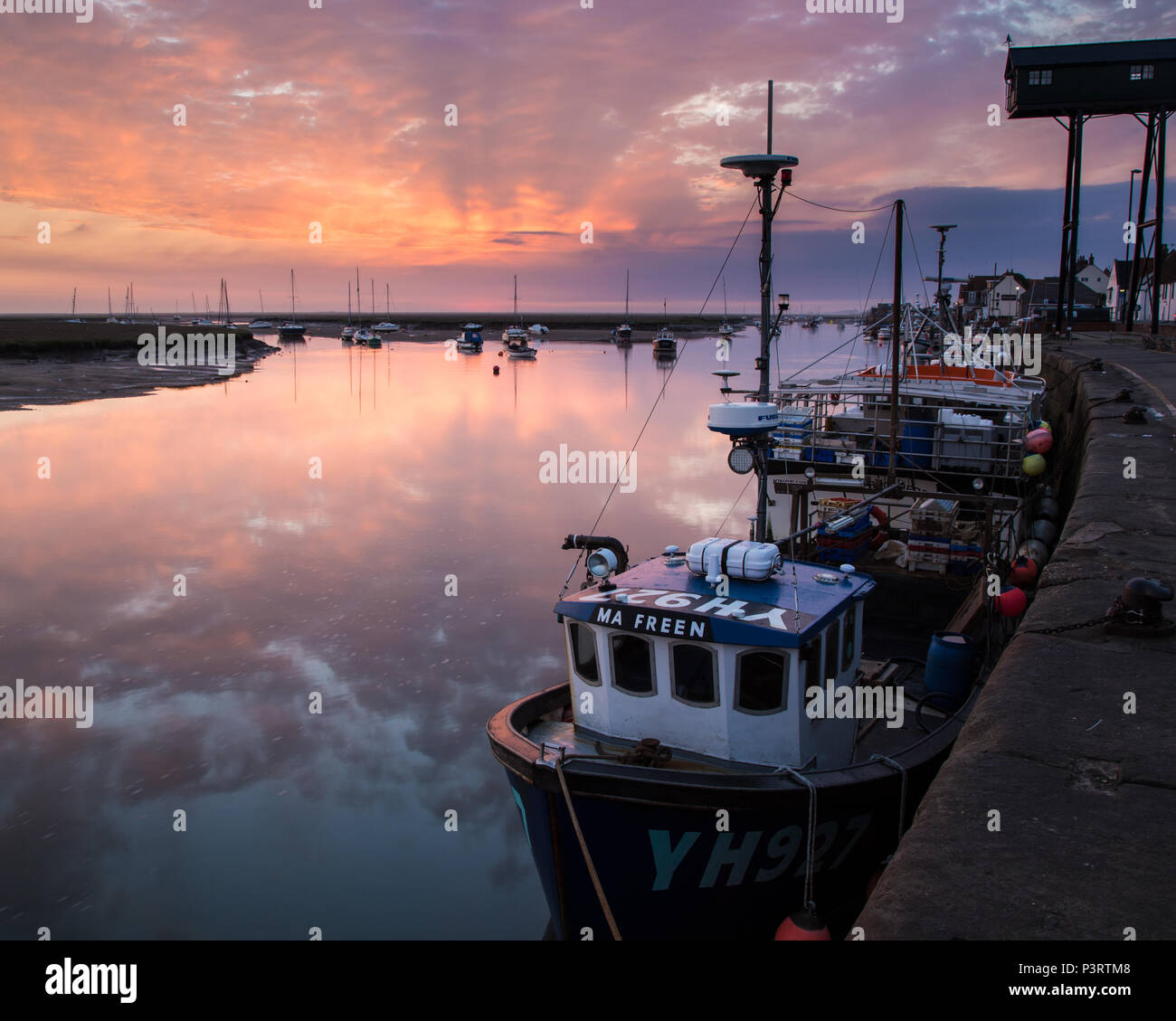 Sunrise over the harbour at Wells next the Sea with a trawler in the foreground. Stock Photo