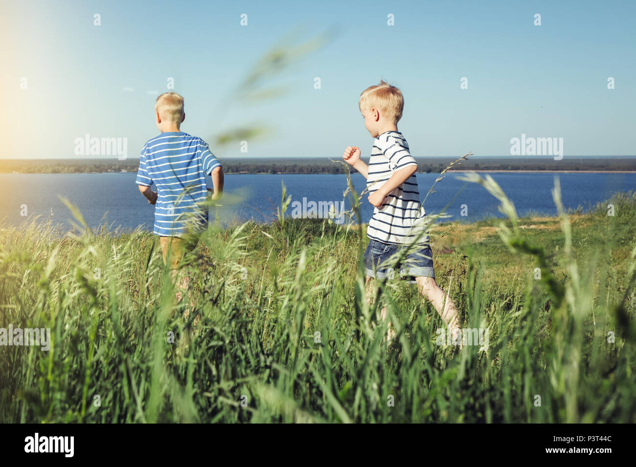 Two boys in striped t-shirts running out on the field. Summer leisure and friendship concept. Stock Photo