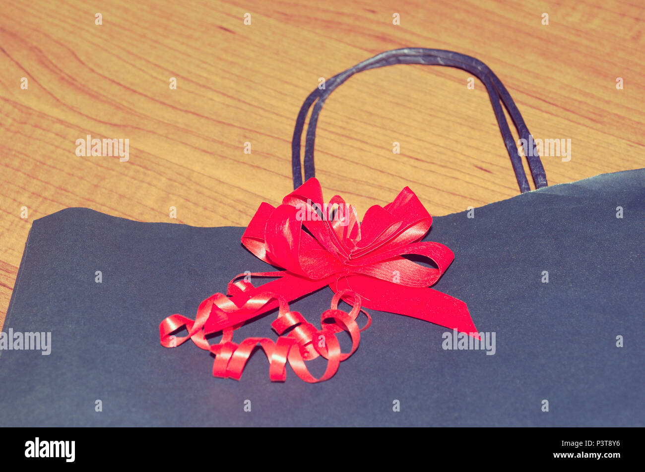 red ribbon on gift paper bag lying on wooden floor Stock Photo