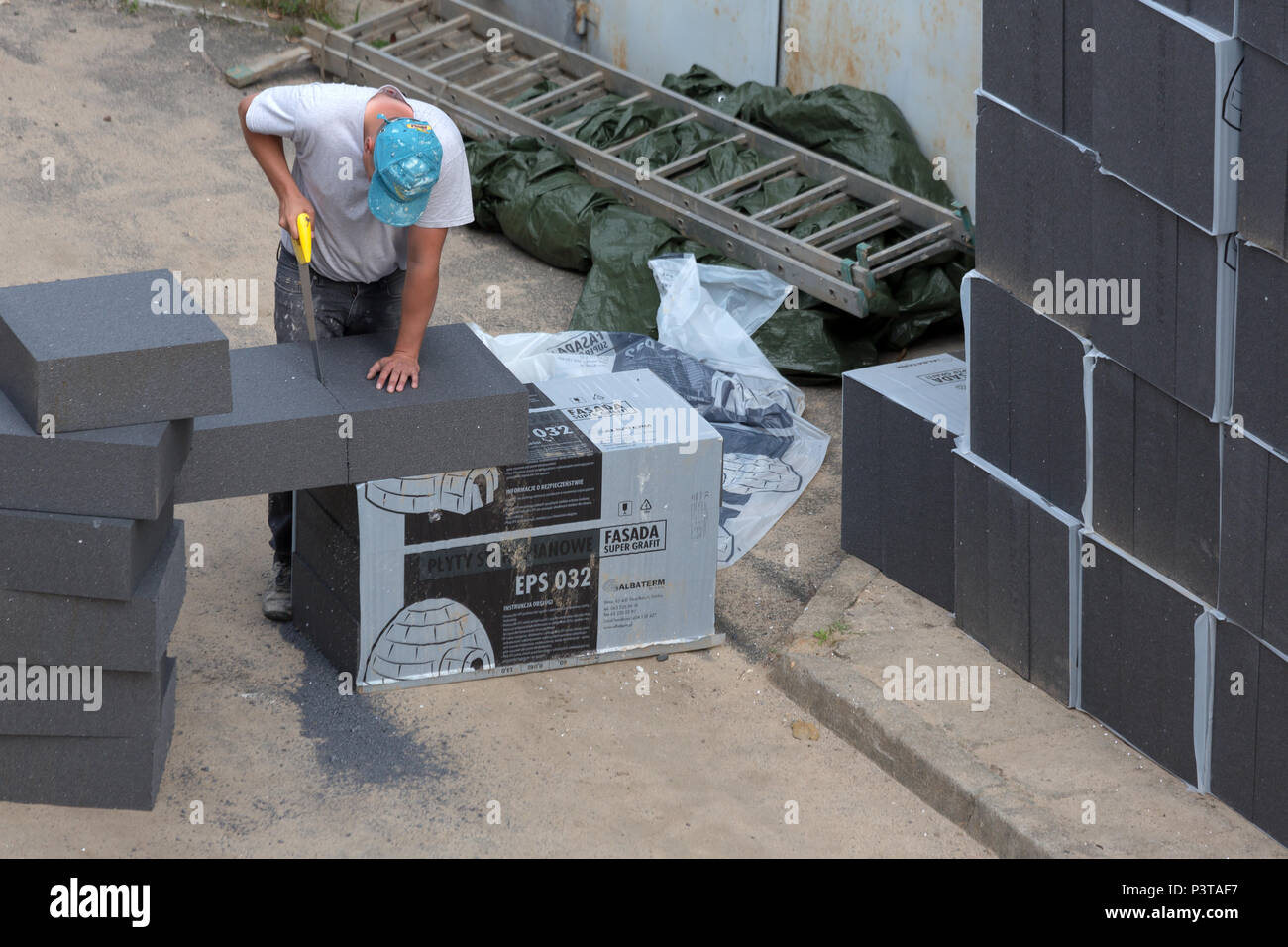 Poland - construction worker is cutting styrofoam for a thermal damaging measure on an old building Stock Photo