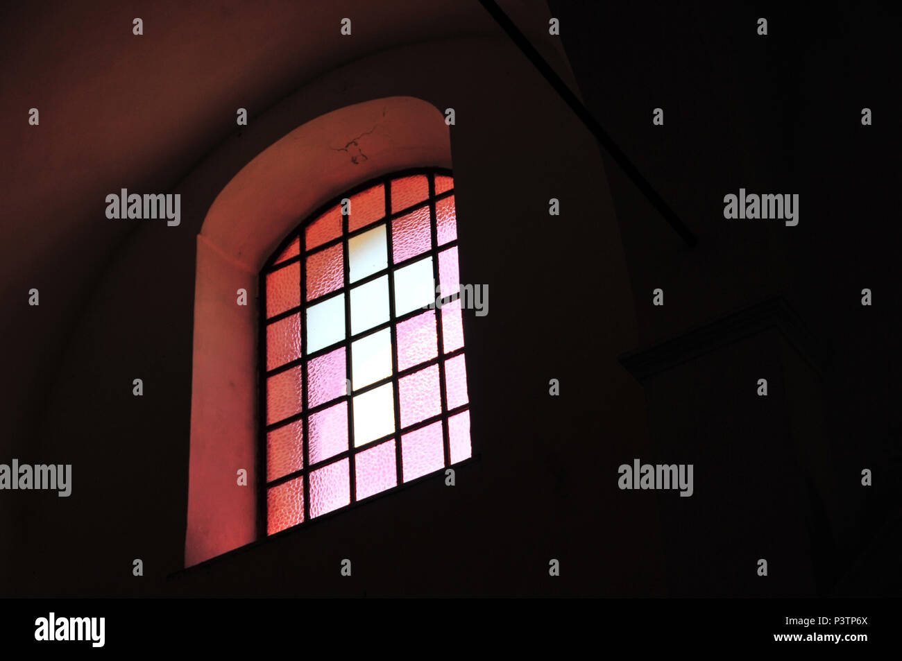 Cross in stained glass window, light in dark Catholic Church Stock Photo