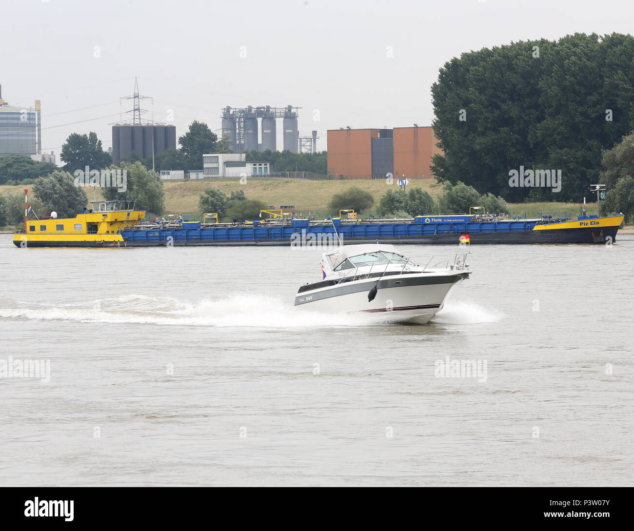 Duisburg, Germany. 19th June, 2018. A cruiser passes the leaking caustic soda tanker 'Piz Ela' (back) on the Rhine at Duisburg. A second tanker is supposed to take over the load so the stranded vessel becomes lighter and might get out. Credit: Roland Weihrauch/dpa/Alamy Live News Stock Photo