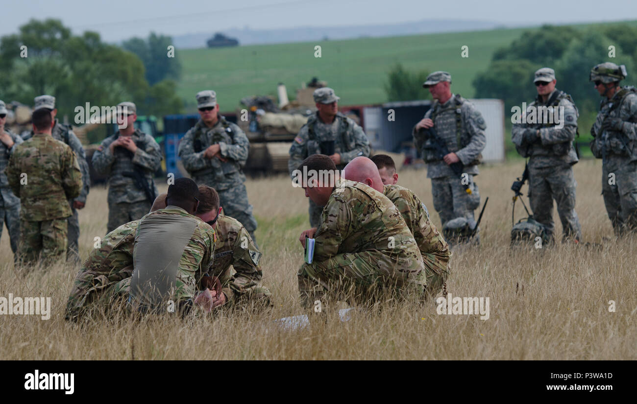 Soldiers with 3rd Battalion, 501st Aviation Regiment plan an air assault mission while Soldiers with Company C, 2nd Battalion, 116th Cavalry Brigade Combat Team wait for cold load training during Saber Guardian 2016 at the Romanian Land Forces Combat Training Center in Cincu, Romania, July 30. Saber Guardian 2016 is a multinational military exercise involving approximately 2,800 military personnel from ten nations including Armenia, Azerbaijan, Bulgaria, Canada, Georgia, Moldova, Poland, Romania, Ukraine and the U.S. The objectives of this exercise are to build multinational, regional and join Stock Photo