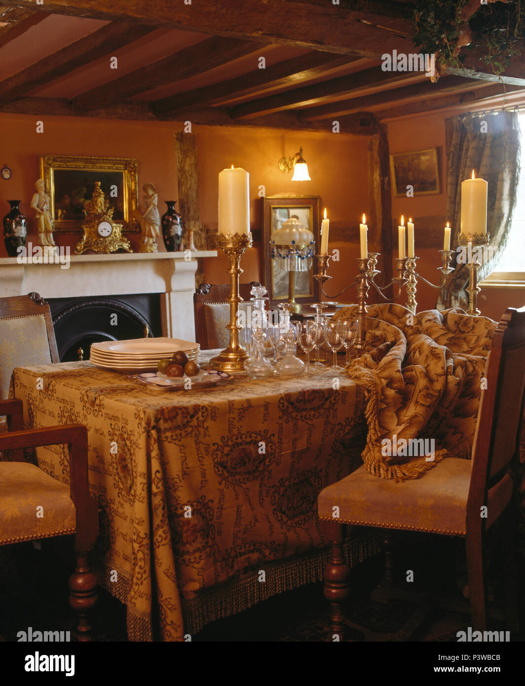Brass candlesticks with lighted candles on table with ochre fringed