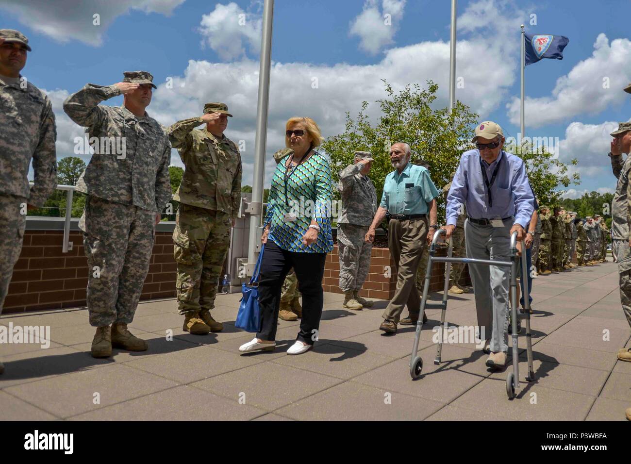 Raleigh, North Carolina – WWII Veterans of the 30th Infantry Division and their families’ walk down a path lined with current North Carolina National Guardsmen rendering salutes in front of Joint Force Headquarters in Raleigh, North Carolina, July 29, 2016. The day marked the beginning of the 30th Infantry Division Association’s 70th Reunion. (U.S. Army Photo by Staff Sgt. Mary Junell) Stock Photo