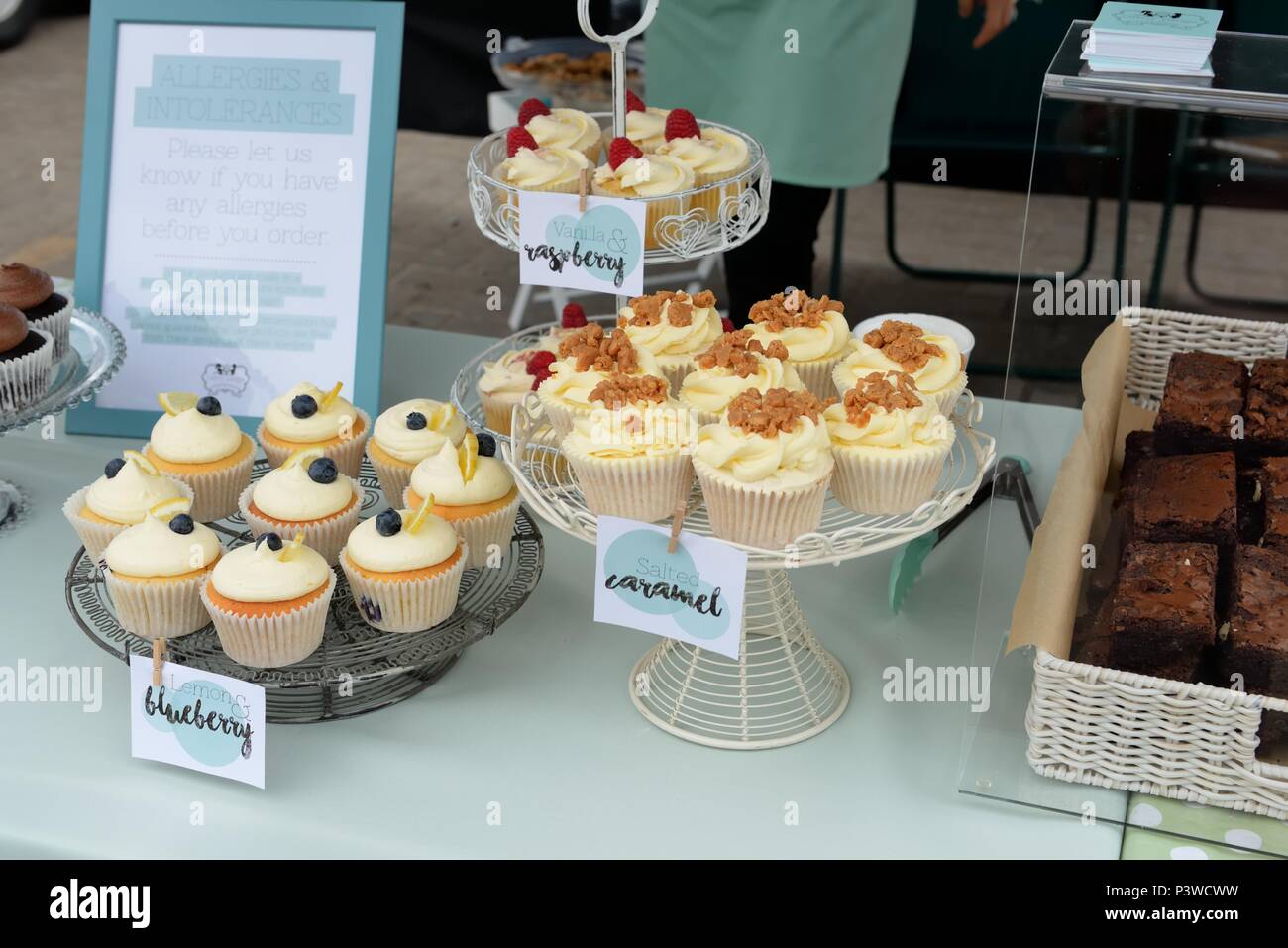 Cake stands at a local food fair in Portree, Skye, Scotland, with assorted fresh cupcakes and a notice warning of possible nut allergy contents. Stock Photo