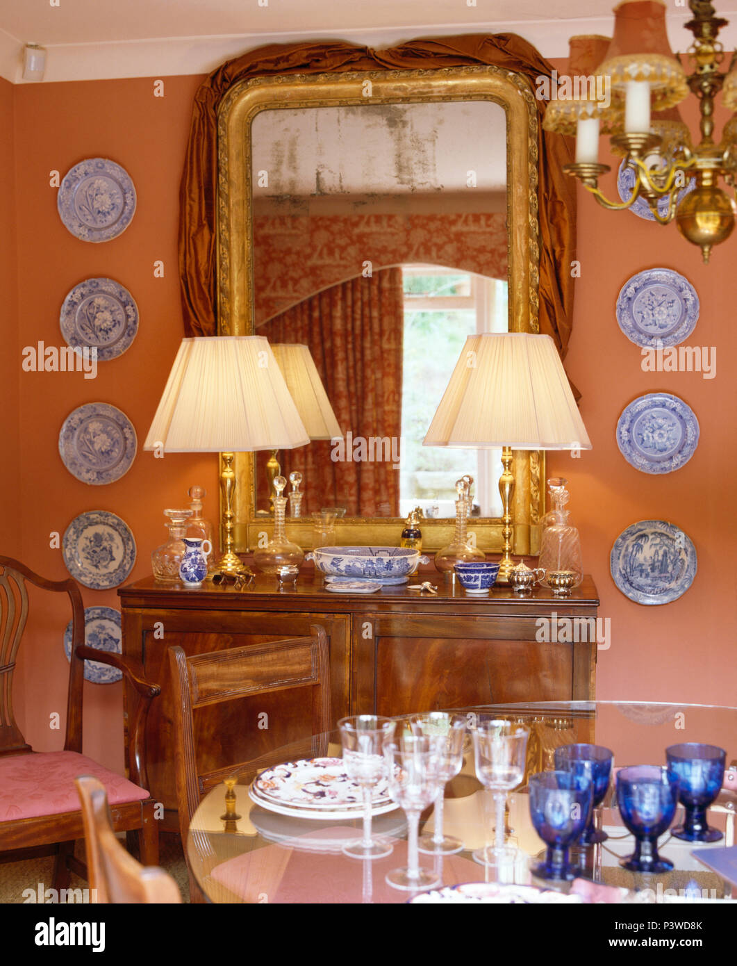 Collection of blue+white plates on either side of antique mirror on ...