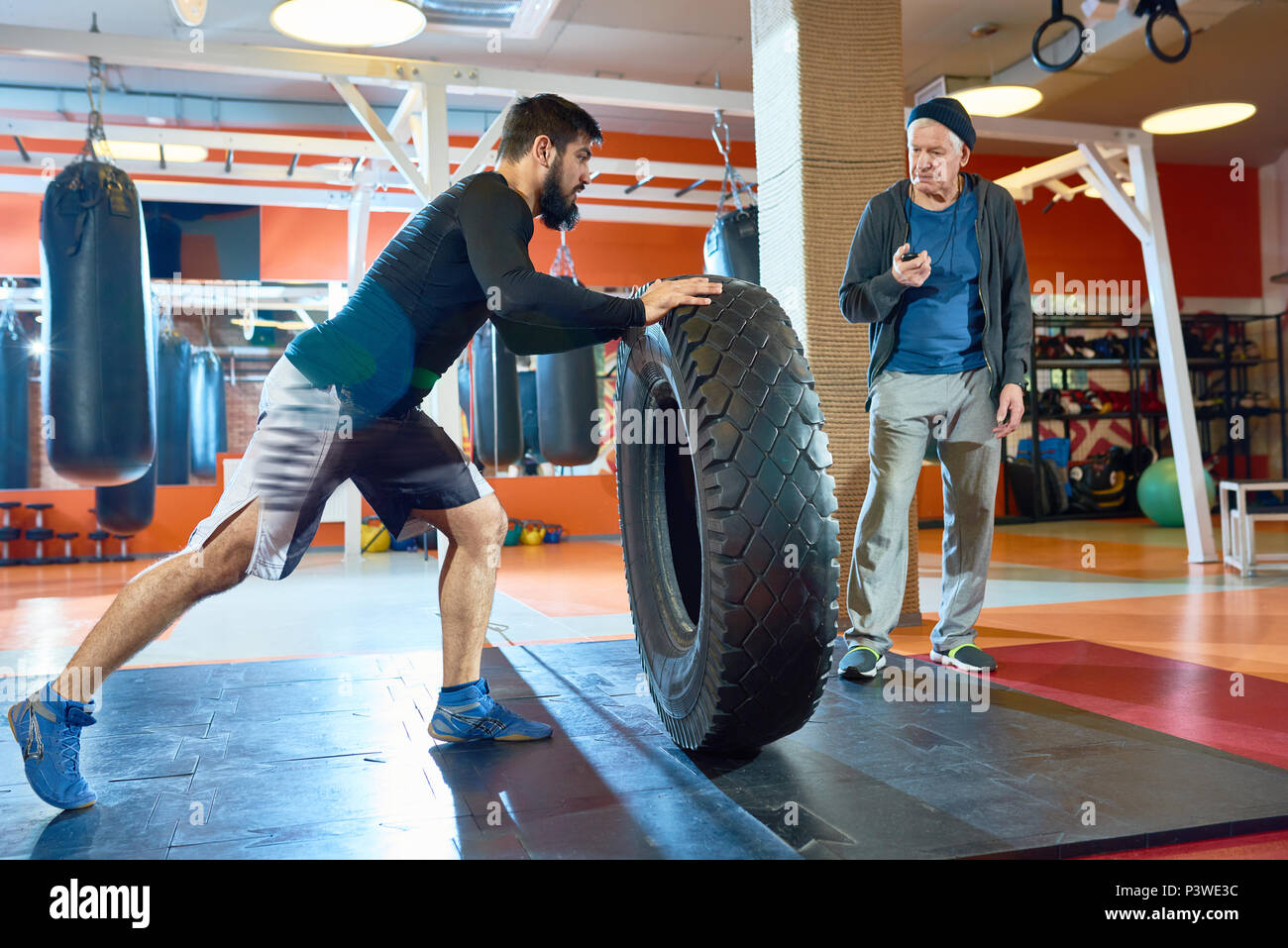 Sportsman flipping huge tyre in gym Stock Photo
