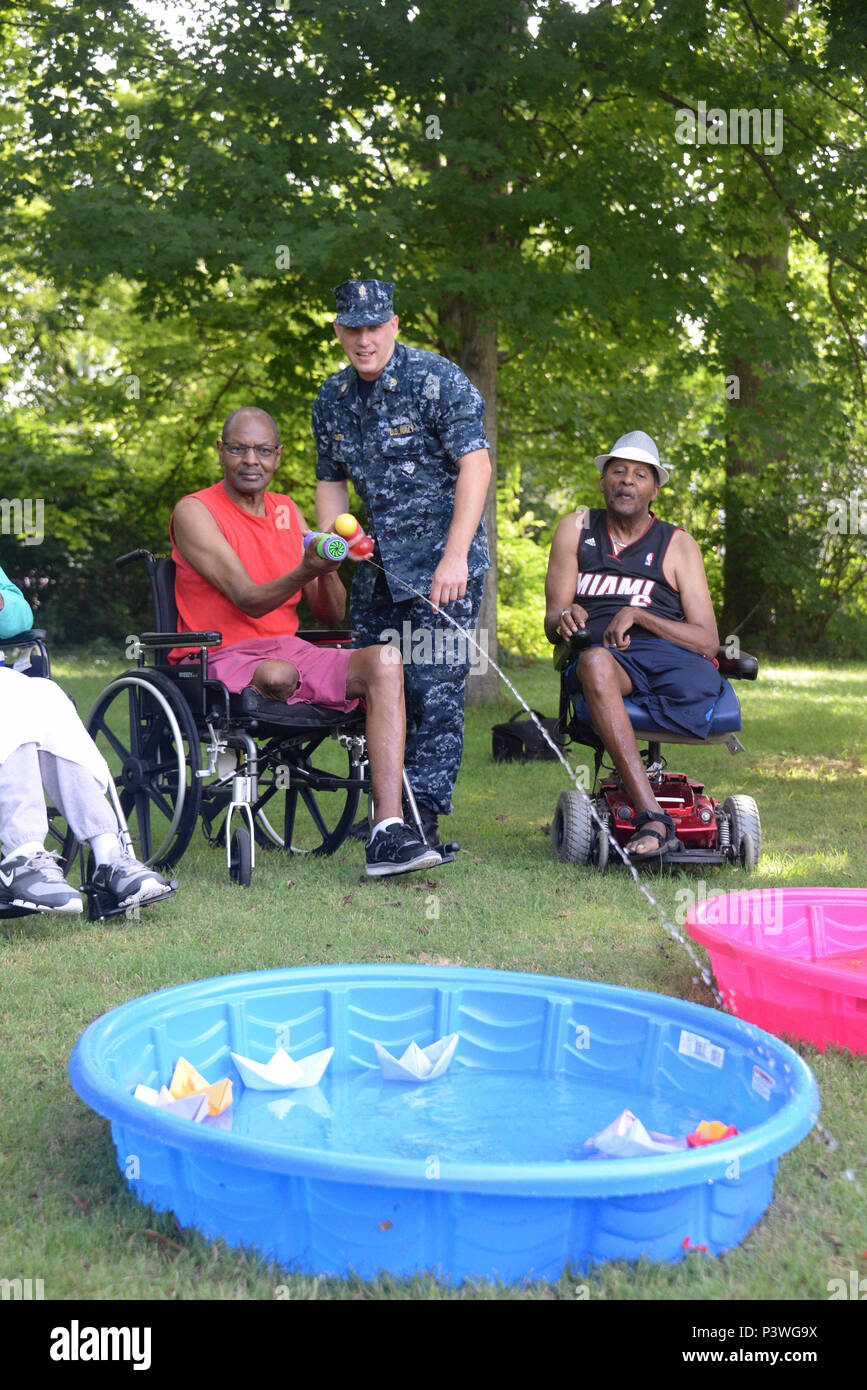 160722-N-FU443-008 NASHVILLE (July 22, 2016) Chief Electrician's Mate (Nuclear) Jeremy Smith assists during an outdoor game where residents attempted to sink paper battleships with squirt guns and water balloons at the Azalea Trace Assisted Living facility. Several members of Navy Recruiting District Nashville volunteered for the event in order to reach out to local members of the community. (U.S. Navy photo by Mass Communication Specialist 1st Class Timothy Walter/Released) Stock Photo