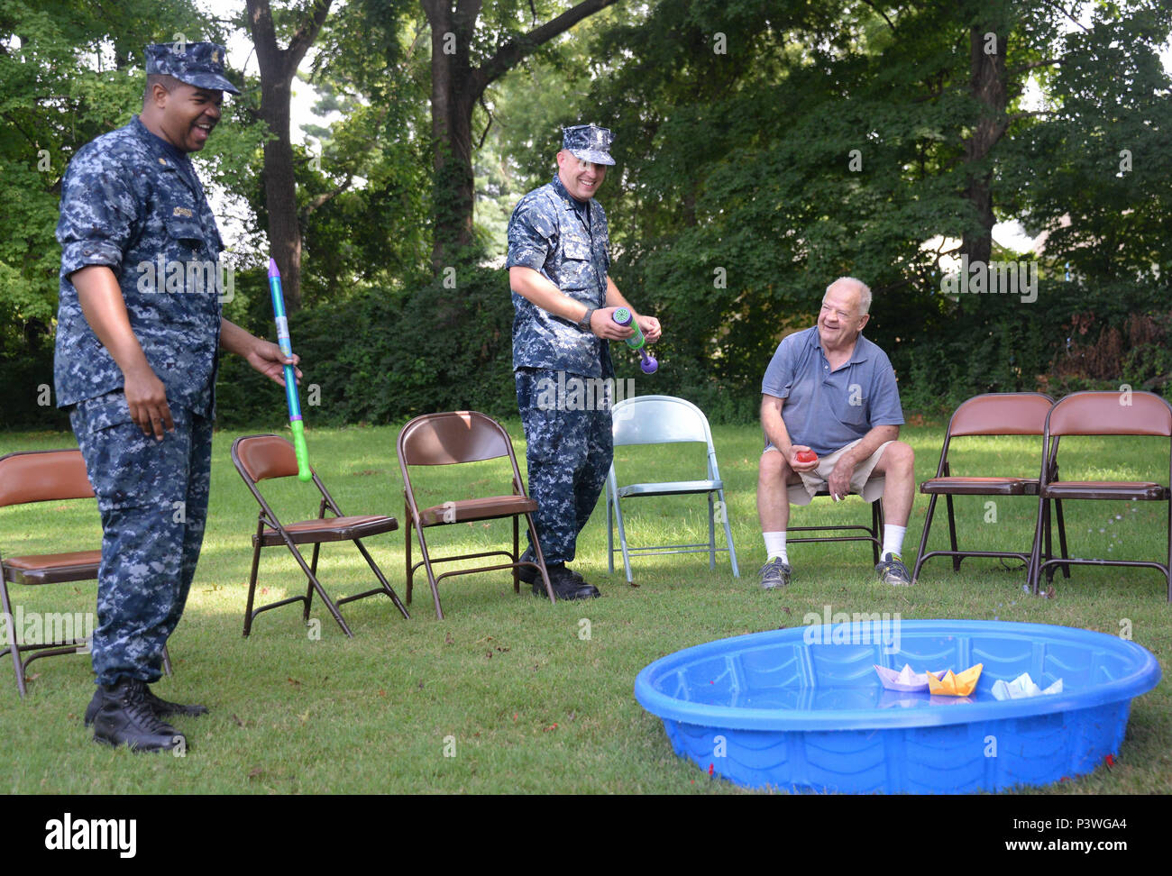 160722-N-FU443-009 NASHVILLE (July 22, 2016) Chief Electrician's Mate (Nuclear) Jeremy Smith, center, and Chief Aviation Boatswain’s Mate (Handling) Mario Johnson, left, assist during an outdoor game where residents attempted to sink paper battleships with squirt guns and water balloons at the Azalea Trace Assisted Living facility. Several members of Navy Recruiting District Nashville volunteered for the event in order to reach out to local members of the community. (U.S. Navy photo by Mass Communication Specialist 1st Class Timothy Walter/Released) Stock Photo
